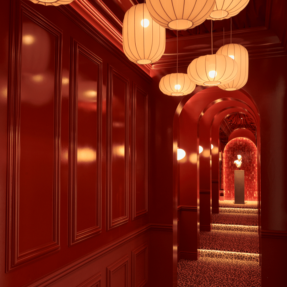 Decorative hallway with red walls, hanging lights, and a patterned floor.